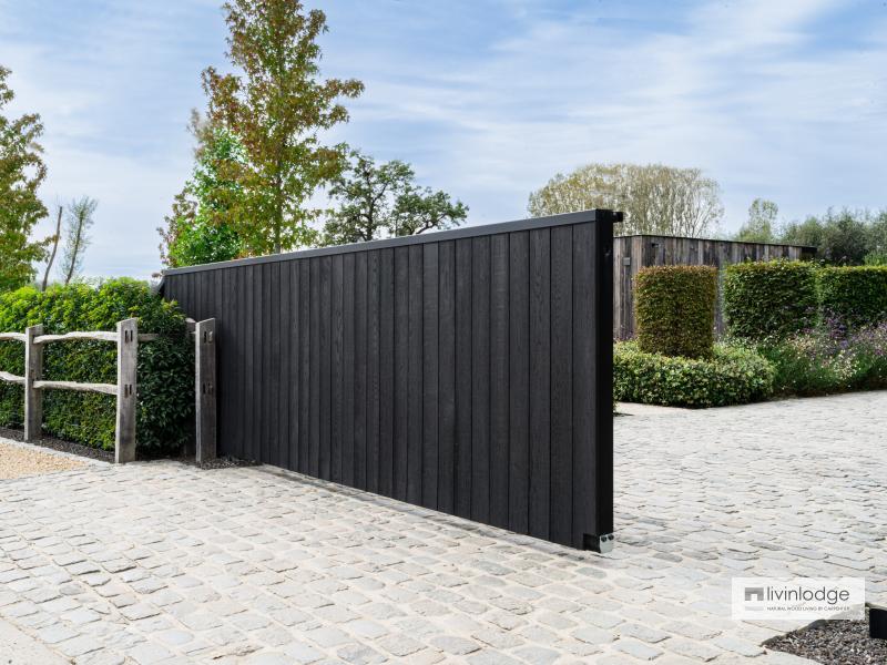 Sliding gate in black wood blending with nature